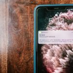 Celular exibindo uma notificação de alerta sobre fraude sobre uma superfície de madeira.